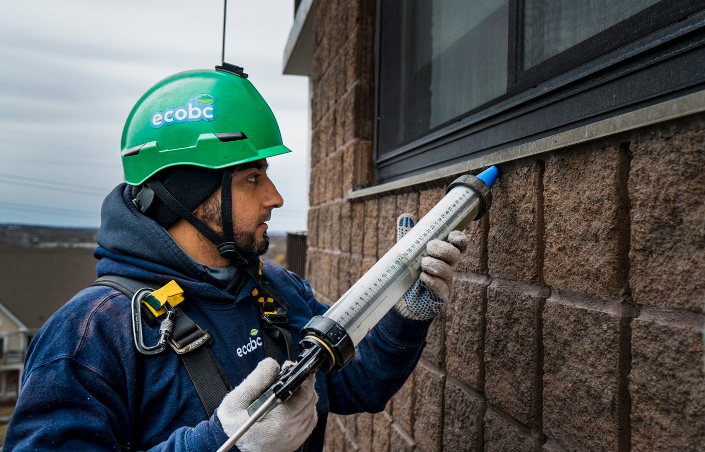 ecobc technician recaulking a building envelope from a swing stage