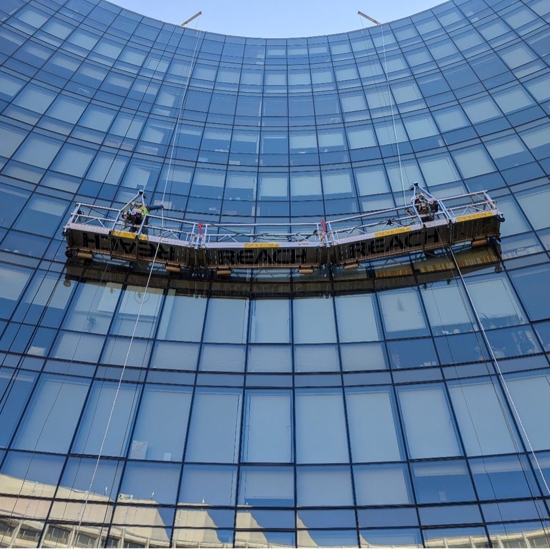 ecobc swing stage performing curtain wall sealant maintenance on a glass tower